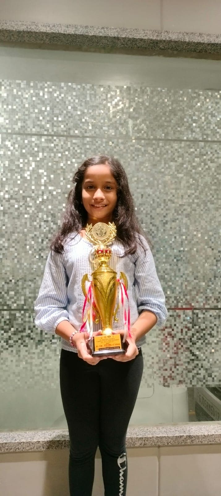 Prisha Shah smiling at chess board with trophies